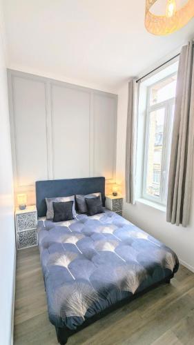 une chambre avec un lit avec une couette bleue et une fenêtre dans l'établissement L'haussmannien 1er Étage, à Abbeville