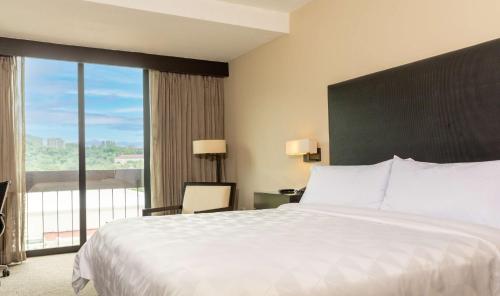 a bedroom with a large bed and a large window at Hilton San Salvador in San Salvador