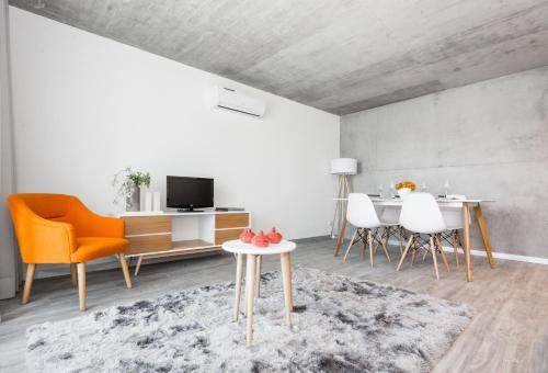a living room with an orange chair and a table at Innapartments - São Gonçalinho in Aveiro