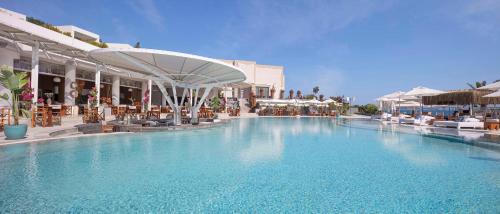 a large swimming pool in a resort with tables and chairs at Susona Bodrum, LXR Hotels & Resorts in Torba