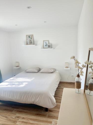 - une chambre avec un lit aux murs blancs et du parquet dans l'établissement Bel appartement dans hameau calme, à Bonifacio