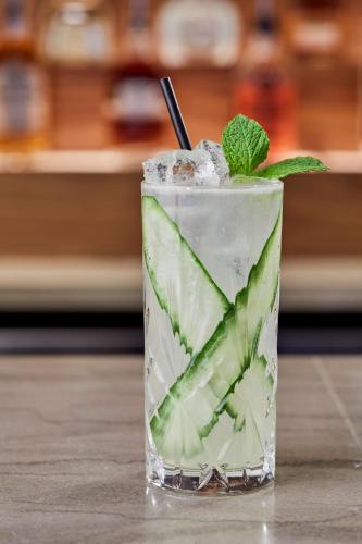 a drink with cucumbers in a glass on a table at Cumberland House Knoxville, Tapestry Collection by Hilton in Knoxville