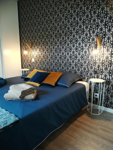 - une chambre avec un lit bleu et un mur à motifs dans l'établissement Meublé 3 étoiles Les Capucines, à Plouescat
