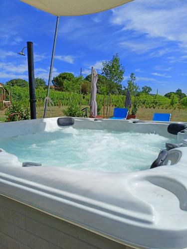a jacuzzi tub with an umbrella and chairs at La Casa della Nonna in Brisighella