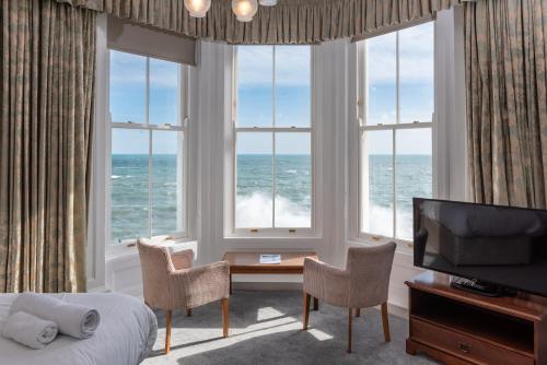 a room with a bed and a view of the ocean at The Queens Hotel in Penzance