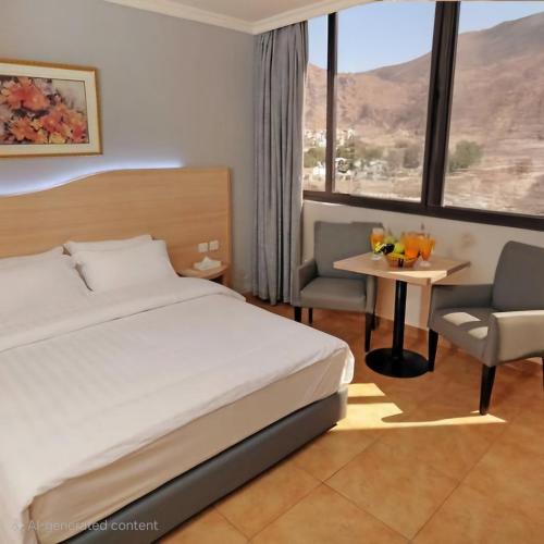 アカバにあるGolden Lotus hotel Aqabaのベッドとテーブルと椅子のある寝室