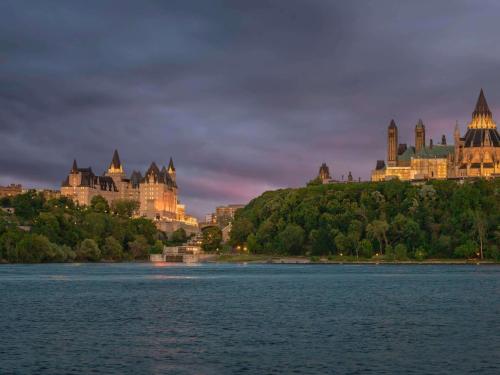 a castle on a hill next to a body of water at Fairmont Chateau Laurier in Ottawa