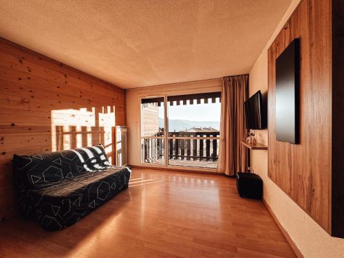 Una sala de estar con un sofá y una ventana grande. en Le cocon des 4 saisons Appartement cosy et chaleureux, proche des pistes, en Font-Romeu