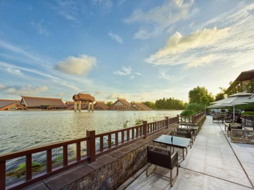 a dock with tables and chairs next to a body of water at Hilton Shanghai Songjiang Guangfulin in Songjiang