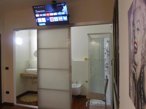 a bathroom with a toilet and a tv on the wall at B&B Golfo Asinara Suite & Relax in Sorso