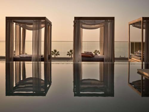 a room with two beds and a swimming pool at The Royal Senses Resort & Spa Crete, Curio Collection by Hilton in Panormos Rethymno