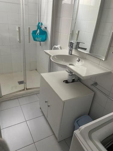 une salle de bain blanche avec un lavabo et une douche dans l'établissement Location Appartement LA TRANCHE SUR MER, à La Tranche-sur-Mer