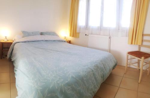 une chambre avec un lit avec une couette bleue et une fenêtre dans l'établissement Logement indépendant, proche gare, à Aubergenville