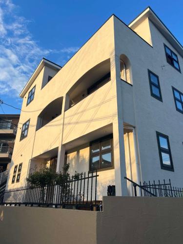 a white building with a fence in front of it at Cielito Hayama 最大10名 海まで10分 テラスBBQ 葉山の空と海と富士山に出会うヴィラ in Hayama