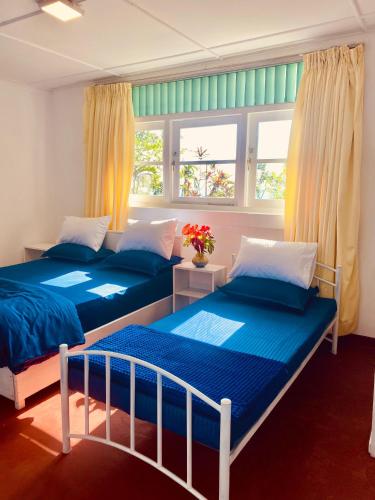 two beds in a room with two windows at Crystal Villa Knuckles in Kandy