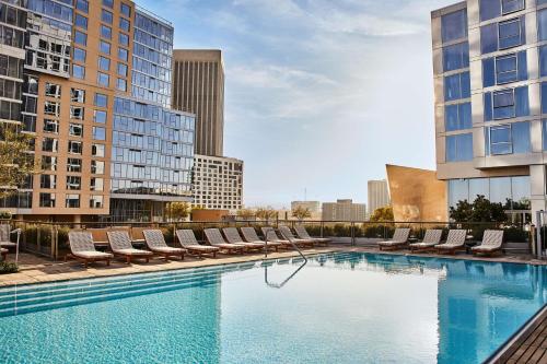 a large swimming pool with lounge chairs and buildings at Conrad Los Angeles in Los Angeles