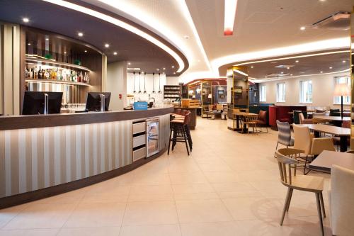 a restaurant with a bar and tables and chairs at Hampton By Hilton Regensburg in Regensburg