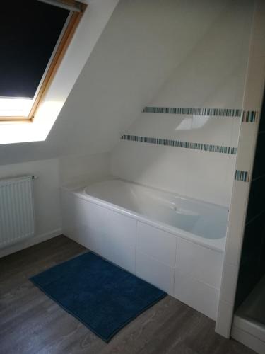 La salle de bains est pourvue d'une baignoire blanche et d'une fenêtre. dans l'établissement Meublé 3 étoiles Les Capucines, à Plouescat