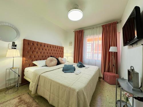 a bedroom with a large bed and a television at Spacious 3BR Walk to Beach & Old Town Marbella in Marbella
