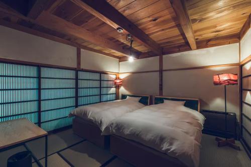 a bedroom with two beds in a room with wooden ceilings at 海ノ離レ in Matsue