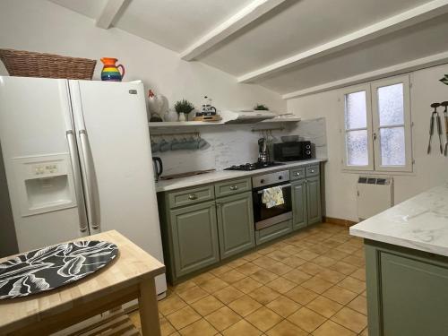 une cuisine avec des armoires vertes et un réfrigérateur blanc dans l'établissement village house, 2 terrace & Air conditioner, à Soubès