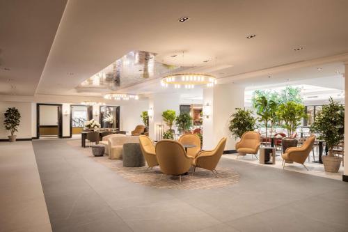 a lobby with a waiting area with chairs and tables at Hilton Heidelberg in Heidelberg