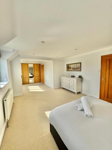 a large white bedroom with a bed and a dresser at Stunning 7 Bedroom Escape Near New Forest and Beach - Large Garden - Serene Setting - Sleeps 14 in Sway