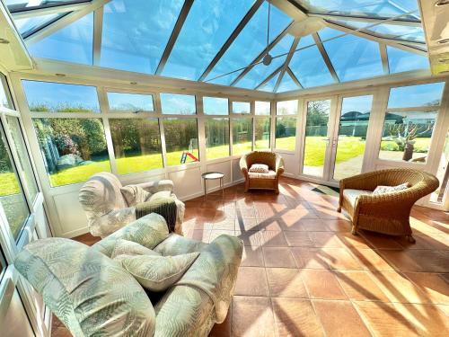 a conservatory with couches and chairs in a room with windows at Stunning 7 Bedroom Escape Near New Forest and Beach - Large Garden - Serene Setting - Sleeps 14 in Sway