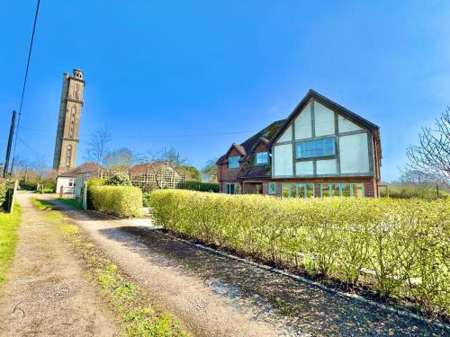 a large house with a clock tower in the distance at Stunning 7 Bedroom Escape Near New Forest and Beach - Large Garden - Serene Setting - Sleeps 14 in Sway
