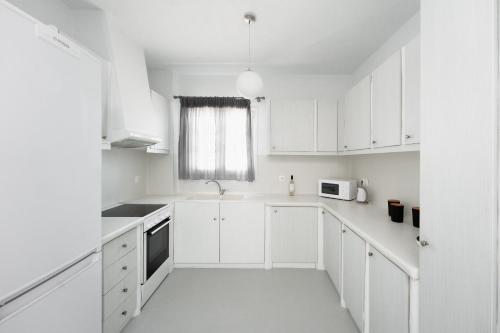 a white kitchen with white cabinets and a window at Niko's home in Adamas