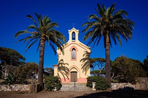 une église avec deux palmiers devant elle dans l'établissement Le Hameau Des Pesquiers Ecolodge & Spa, Curio Collection By Hilton, à Hyères