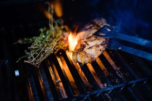 a piece of meat cooking on a grill with flames at Le Hameau Des Pesquiers Ecolodge & Spa, Curio Collection By Hilton in Hyères