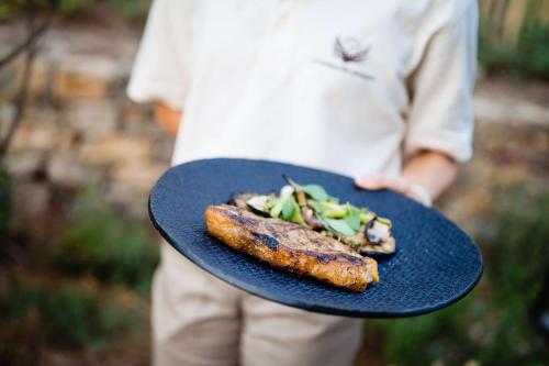 a person holding a blue plate with food on it at Le Hameau Des Pesquiers Ecolodge & Spa, Curio Collection By Hilton in Hyères