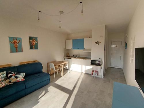 a living room with a blue couch and a kitchen at En Allusi Apartment in Badesi