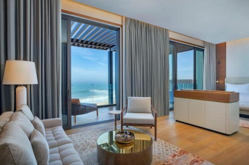 a living room with a couch and a room with a view of the ocean at Conrad Rabat Arzana in Rabat