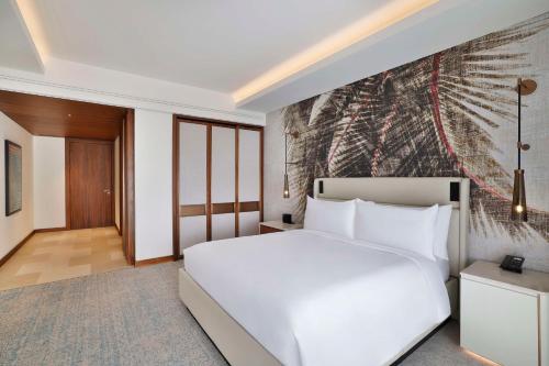 a bedroom with a white bed and a painting on the wall at Conrad Rabat Arzana in Rabat