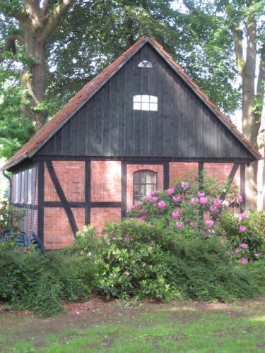 a small house with a black roof and some flowers at Hof Heisterbusch in Groß Fredenbeck