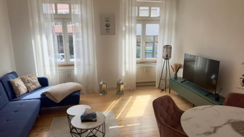 a living room with a blue couch and a tv at Design Apartment Hindenburg in Neustadt an der Weinstrasse in Neustadt an der Weinstraße