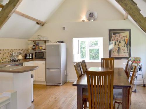 a kitchen with a table with chairs and a refrigerator at Beautiful Dartmoor cottage overlooking vineyard in Bridford
