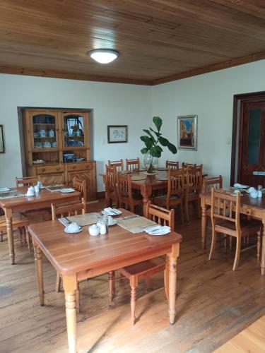 a dining room with wooden tables and wooden chairs at Berg en Zee Guesthouse in Gordonʼs Bay