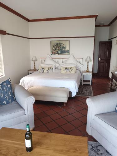 a bedroom with a bed and two couches at Berg en Zee Guesthouse in Gordonʼs Bay