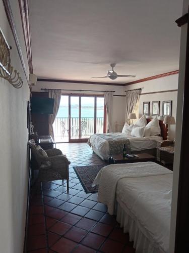 a hotel room with two beds and a balcony at Berg en Zee Guesthouse in Gordonʼs Bay