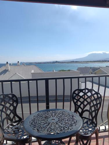 a table and chairs on a balcony with a view of the ocean at Berg en Zee Guesthouse in Gordonʼs Bay