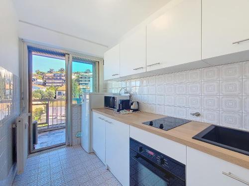 une cuisine avec des appareils blancs et une grande fenêtre dans l'établissement Cocon studio 2pers proche Croisette, Hotel Martinez, Clim, à Cannes