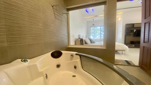 a white bath tub in a bathroom with a bedroom at Willo stays beach cottage in Kannur