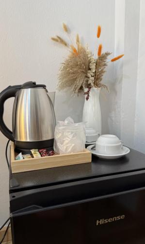 a tea kettle and a vase with flowers on a counter at Brown House Cha am in Cha Am