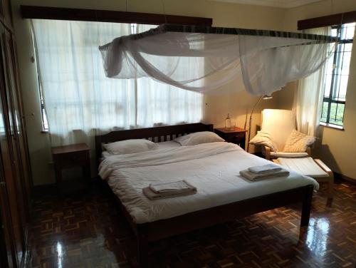 a bedroom with a bed with white sheets and a window at BnB chez Joep - corner Guestroom in Nairobi