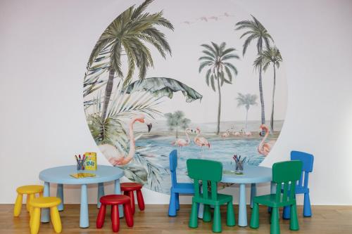 a room with tables and chairs in front of a mural of flamingos at BeachSide in Eckernförde