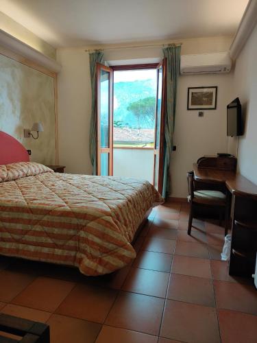 a bedroom with a bed and a desk and a window at Hotel Ristorante da Carlos in Santa Maria del Giudice