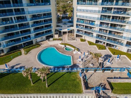 an overhead view of a swimming pool with palm trees and buildings at Ebb Tide 703 in New Smyrna Beach
